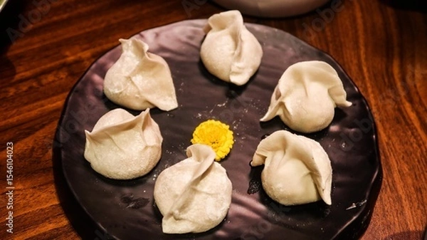 Fototapeta close up of six uncooked raw pork dumplings (Jiaozi or Gyoza) on a plate with a yellow flower in the middle for decoration