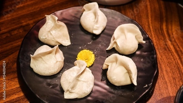 Fototapeta close up of six uncooked raw pork dumplings (Jiaozi or Gyoza) on a plate with a yellow flower in the middle for decoration