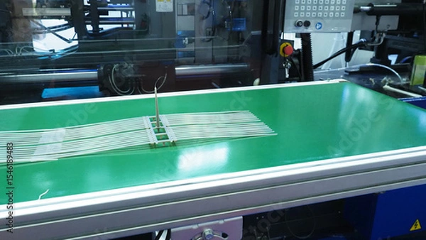 Fototapeta Plastic cable ties produced from an injection molding machine  and placed on a conveyor belt.
