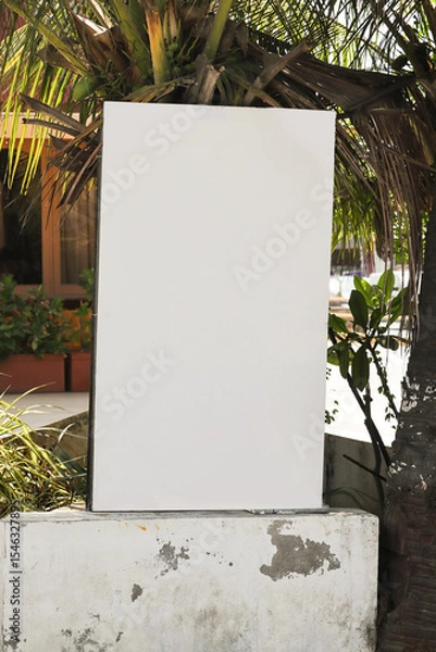 Fototapeta Empty outdoor information board placeholder. Small vertical billboard by the road in a small green city. billboard mock-up near the road; vertical blank advertising banner template on the street