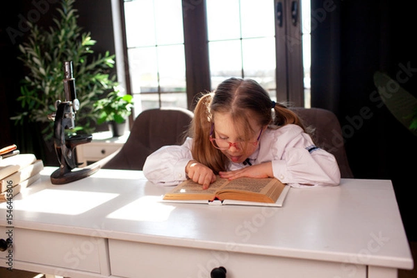 Fototapeta A 7-year-old child in glasses and school uniform poses at the school table indoor