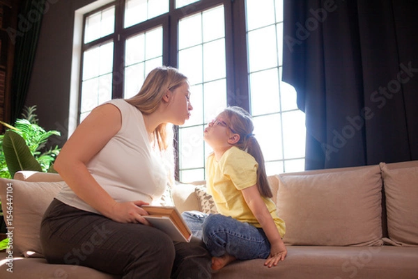 Fototapeta A 7-year-old child in glasses and mother have fun in sofa indoor