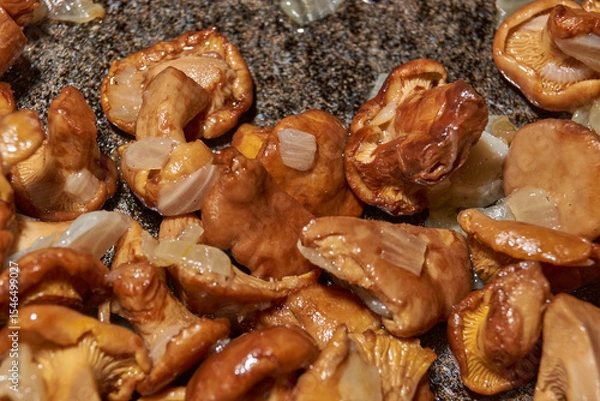Fototapeta Hot mushroom dish – chanterelles fried with onions in oil. A fragrant dish of fried chanterelles and onions in a frying pan. A close–up of fried chanterelles is a simple and delicious meal.