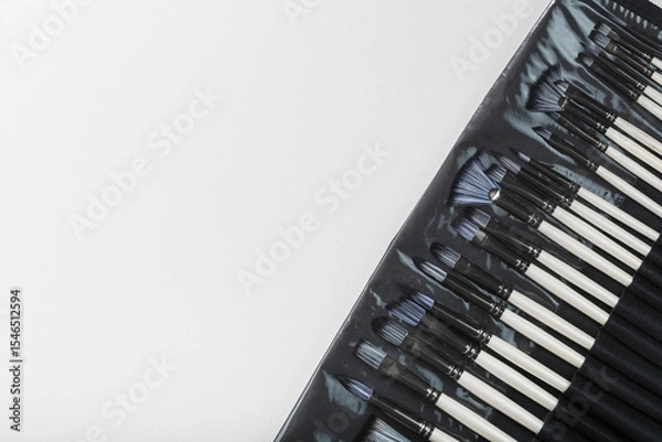 Fototapeta Brushes, palette knives in a pencil case on a white canvas background