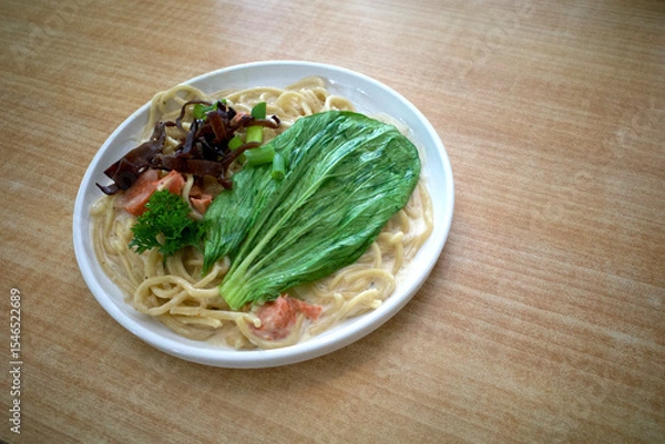Fototapeta A plate of noodle soup with meat. brown mushroom and vegetables on the wooden table