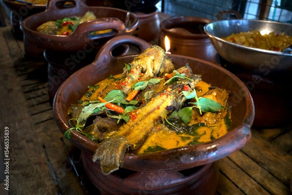 Fototapeta Mangut Lele, delicious catfish stew with yellow sauce, spicy catfish curry with coconut milk on a clay pan