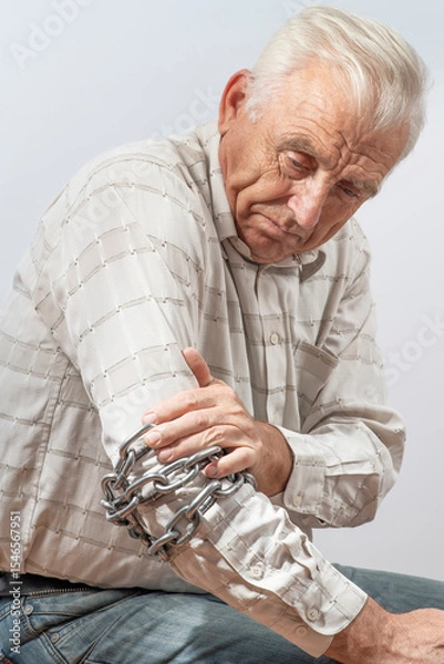 Fototapeta Arthritis symptoms, suffering from pain. The hands of the senior man massage a painful elbow. Chain symbolizing inflamed male joint, stiffness of movement. Old age, health. Close up view..