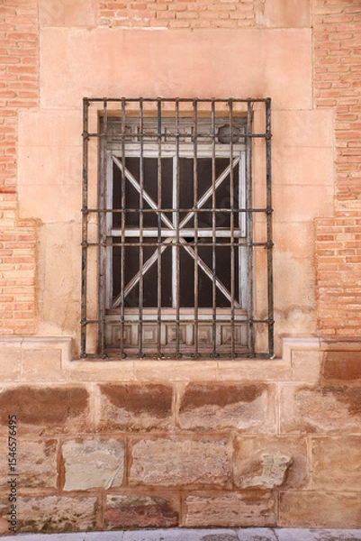 Fototapeta Stone facade with window with wrought iron lattice in Spain