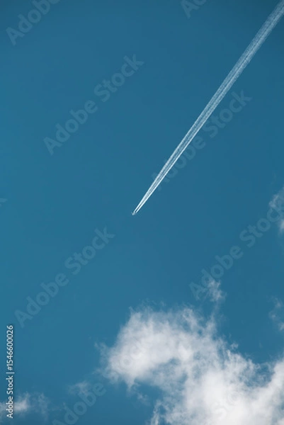 Obraz Commercial airplane flying across deep blue sky with visible contrail