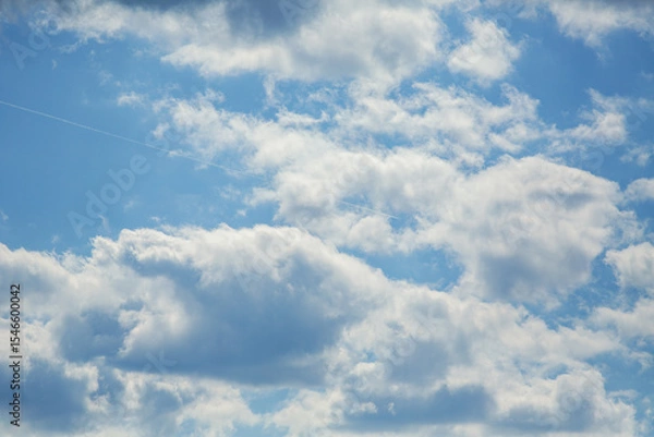 Obraz Airplane flying high among scattered clouds leaving faint contrail