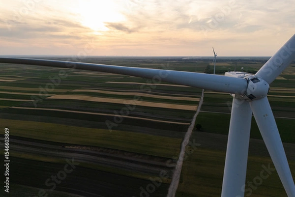 Fototapeta Aerial view of wind turbine on an agricultural filed at sunset. Close up of blades