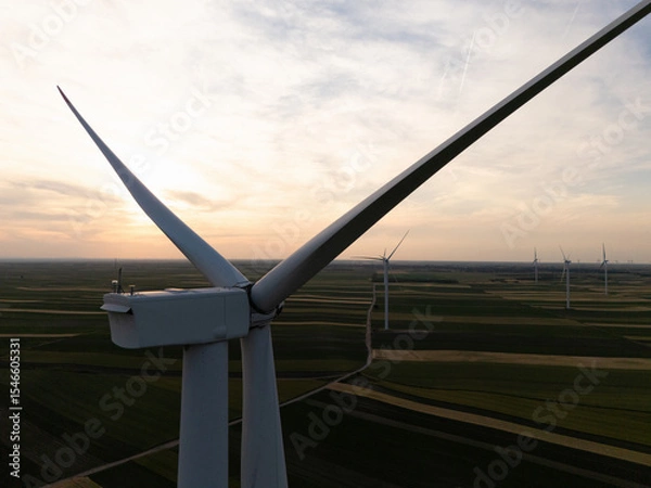 Fototapeta Aerial view of wind turbine on an agricultural filed at sunset. Close up of blades