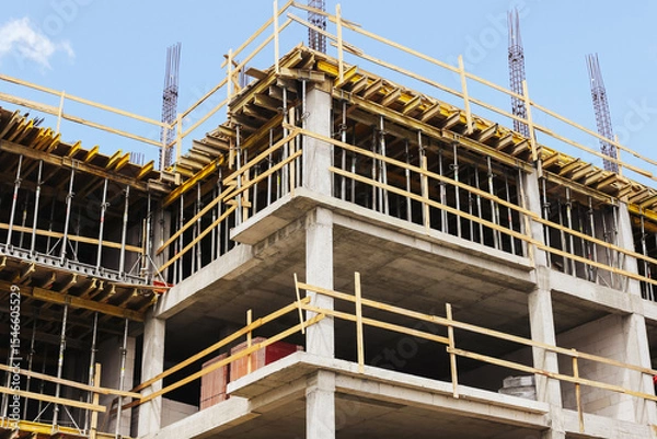 Fototapeta Concrete building under construction. Unfinished structure framework. Modern architecture site view. Reinforced skeleton in progress. Real estate development zone. New apartment block in progress.