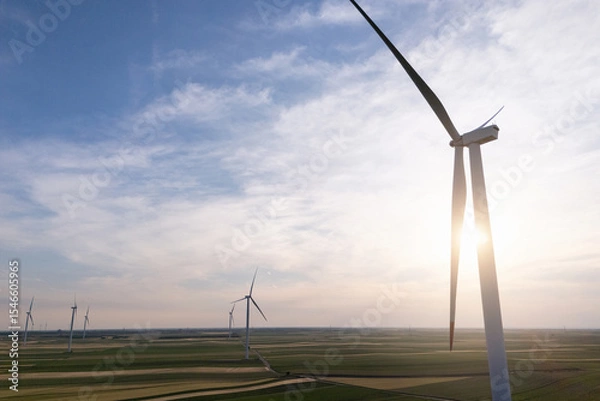 Fototapeta Aerial view of wind turbine on an agricultural filed at sunset. Close up of blades