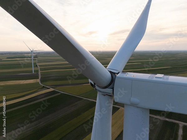 Fototapeta Aerial view of wind turbine on an agricultural filed at sunset. Close up of blades