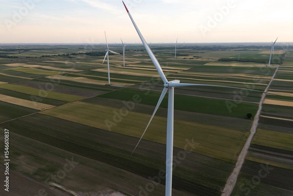Fototapeta Aerial view of wind turbine on an agricultural filed at sunset. Close up of blades