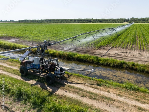 Fototapeta Autonomous machine is moving watering pivot along irrigation canal