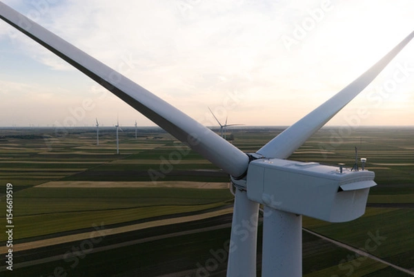 Fototapeta Aerial view of wind turbine on an agricultural filed at sunset. Close up of blades