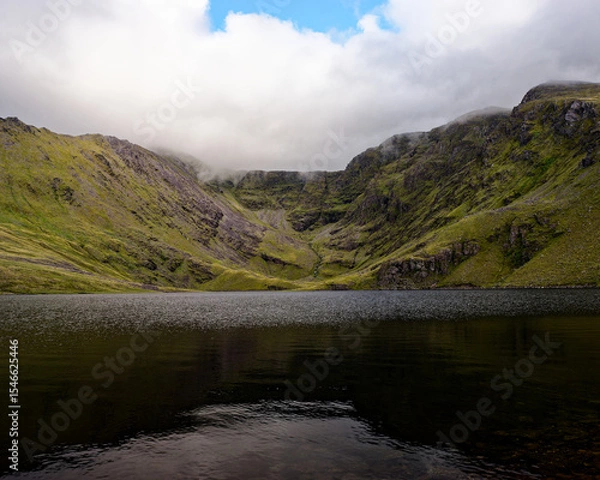 Fototapeta A mystical landscape unfolds, a still lake reflecting misty mountains, wildness and tranquility combined.