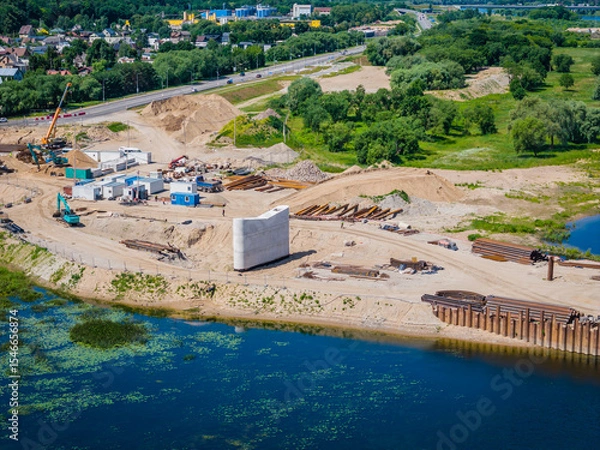 Obraz Construction site of new modern bridge construction in Kaunas, Lithuania. Aerial drone view of bridge connecting two shores of a river. Work progress