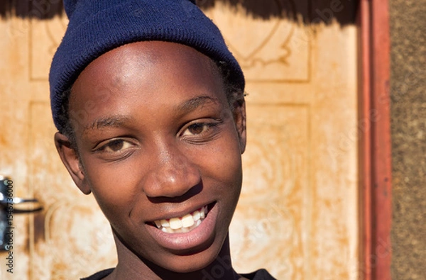 Fototapeta village single young african woman wearing a beanie standing in front of the house , in the yard, close portrait