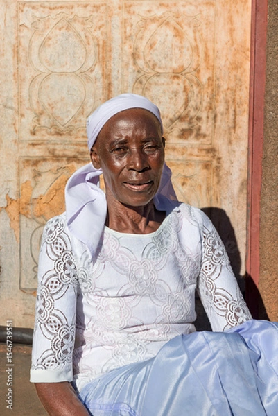 Fototapeta village single zezuru old african woman wearing a headscarf sited in front of the house , in the yard, close portrait