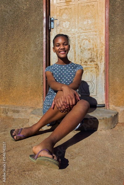 Fototapeta village single young african teenager with braids standing in front of the house , in the yard, close portrait