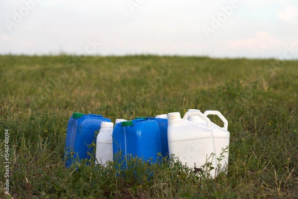 Fototapeta Chemical weeding of the field. Use of herbicides in agriculture. Containers with chemical preparation at the edge of the field after harvesting green fodder.
