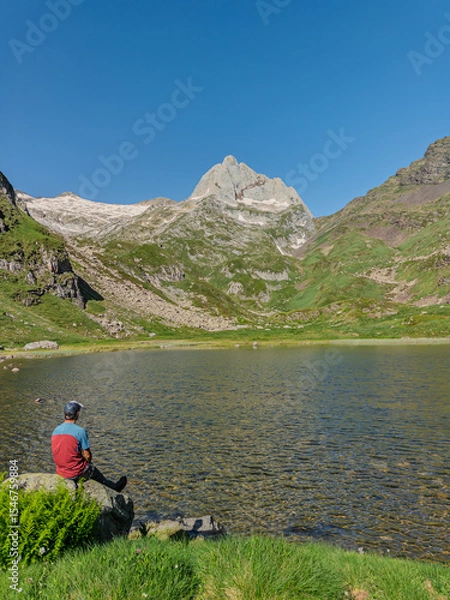 Fototapeta Hiker resting by a mountain lake in the pyrenees.