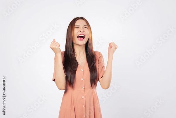 Fototapeta Success empowered by success she celebrates her moment with a raised fist and a bright excited smile showing confidence and professional victory isolated studio white background