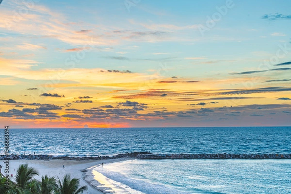 Fototapeta Scenic view of the beach and ocean in Cancun Hotel Zone at sunset with vivid colors in the sky and gentle waves along the shoreline High-quality photo