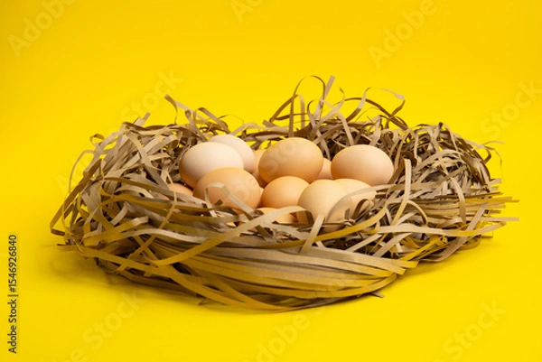 Obraz Brown eggs in paper nest – front view,yellow background