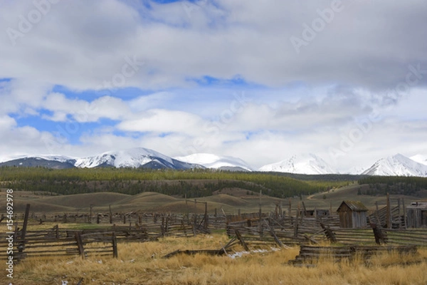 Fototapeta Abandoned Ranch Against Snow Covered Mountain Backdrop