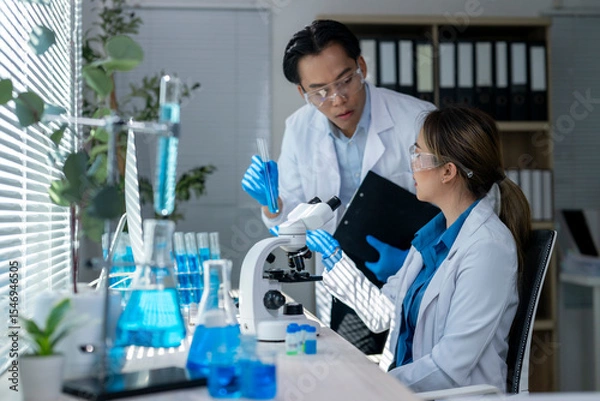 Fototapeta Scientists working with microscope and test tubes doing scientific research in laboratory