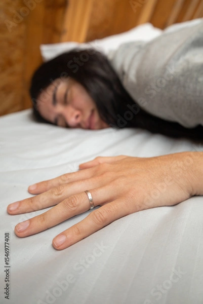 Fototapeta A young woman sleeps face down, resting one hand on the pillow, wrapped in warmth inside a rustic glamping tent. A quiet, intimate moment of deep natural rest.

