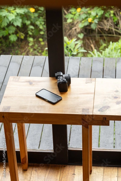 Fototapeta A refined wooden table stands gracefully in front of a large window, flooded with natural light. The scene evokes elegance, serenity, and timeless interior style.


