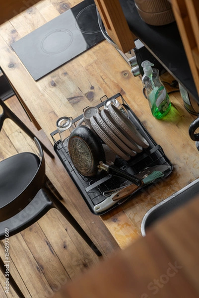 Fototapeta A low-angle shot capturing plates drying neatly on a dish rack inside a warm rustic kitchen, highlighting textures of wood and ceramics bathed in soft natural light.

