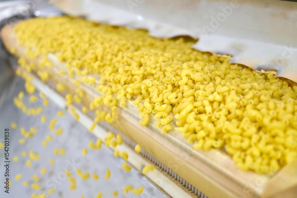 Fototapeta Production process in a bustling pasta manufacturing plant, showcasing vibrant yellow noodles flowing on a conveyor belt