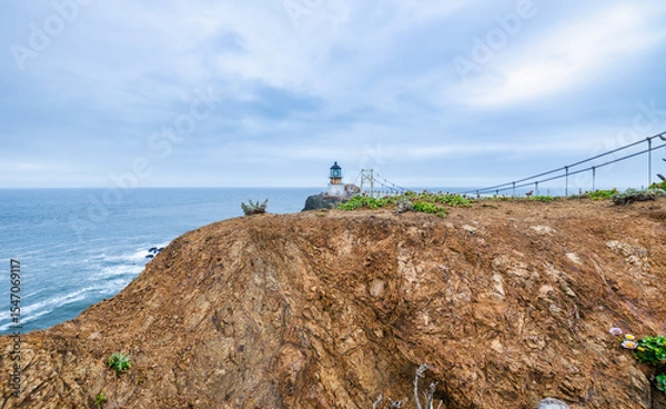 Fototapeta Dramatic coastal view of Point Bonita Lighthouse on a rocky cliff with a suspension bridge and powerful ocean waves, Marin Headlands, California