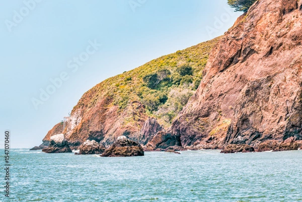 Fototapeta Kirby Cove Beach in California with red sand, blue ocean waves, and dramatic cliffs covered in pine trees. A hidden gem near San Francisco, perfect for nature, travel, and coastal exploration themes