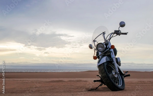 Fototapeta Off-road motorcycle standing still in the open desert beneath heavy clouds. A strong visual of freedom, rugged adventure, and the thrill of riding through wild, untamed terrain.