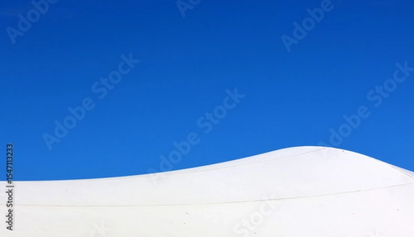 Fototapeta White shade sail canopy against a clear blue sky close-up abstract textured background