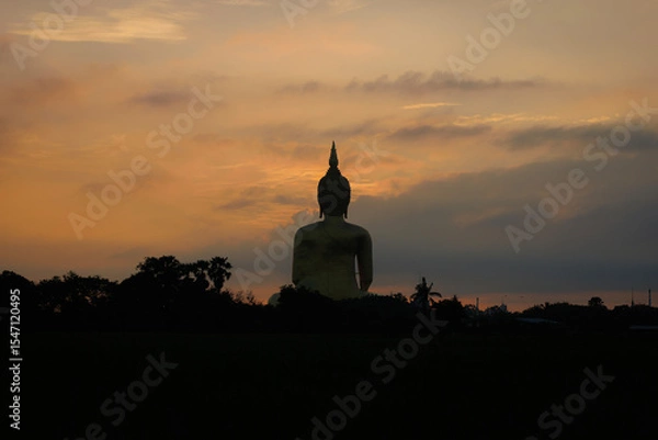 Obraz The largest golden Buddha statue with green rice field foreground at Wat Muang Temple in Ang Thong Province, Thailand.