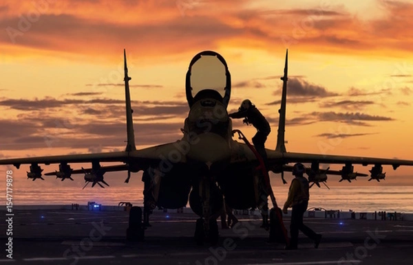 Fototapeta Fighter jet front view silhouette on aircraft carrier at sunset