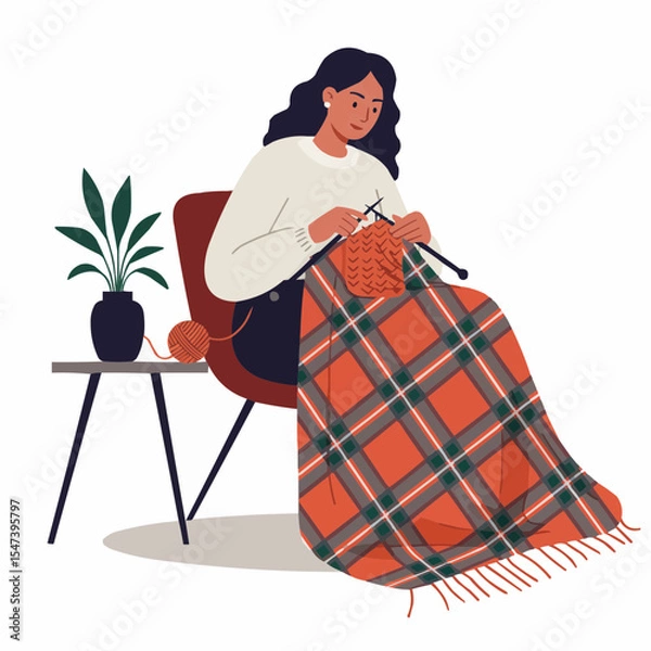 Obraz Young woman knitting a plaid blanket while sitting in a chair indoors  