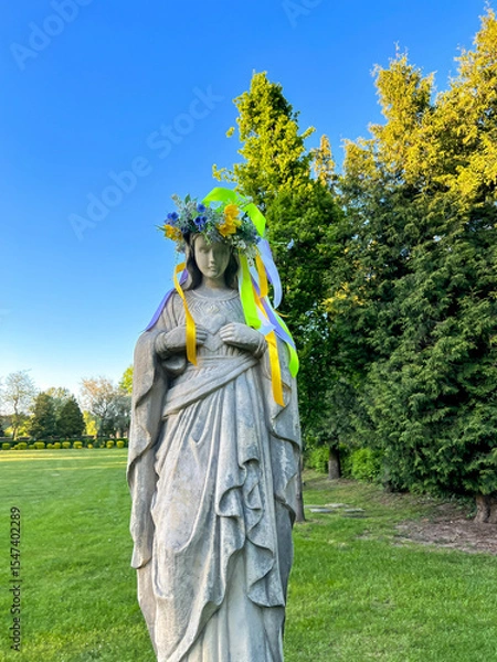 Fototapeta A figure of Mary with a wreath on her head in the garden at the Minor Basilica of Our Lady of Listening Patiently in Rokitno, Poland