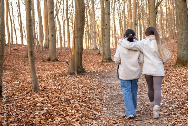 Obraz Two female friends on a walk in the forest. Friends walking through the forest. People in nature.