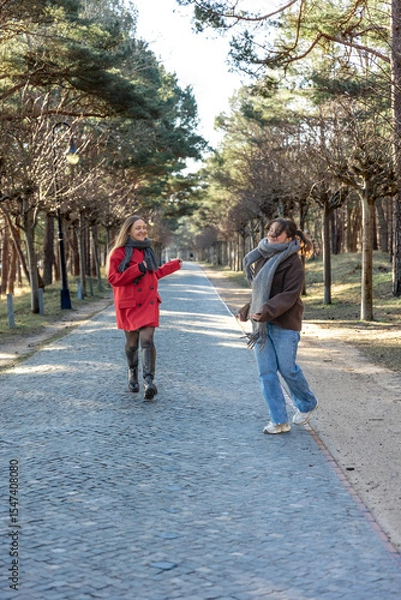 Obraz Two women walking in the park. Friends walking on a path in the park. Nature.