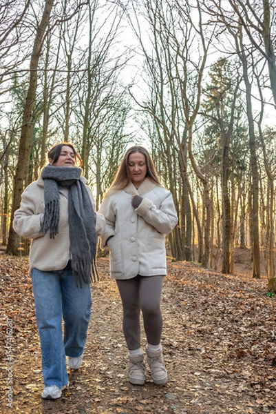 Obraz Two female friends on a walk in the forest. Friends walking through the forest. People in nature.