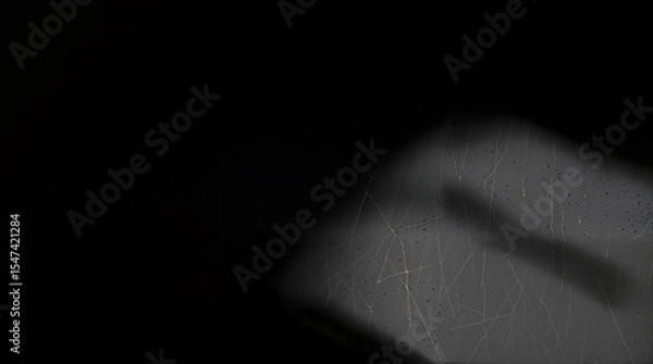 Fototapeta A black and white photo of a dark room. A small area is illuminated, revealing a weathered cement texture